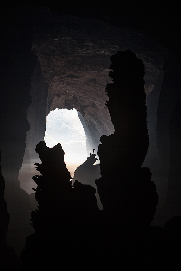 In der Höhle findet man gigantische Stalagmiten von bis zu 80 Metern Höhe. Im Hintergrund stehen 2 Personen auf “Hand of Dog”